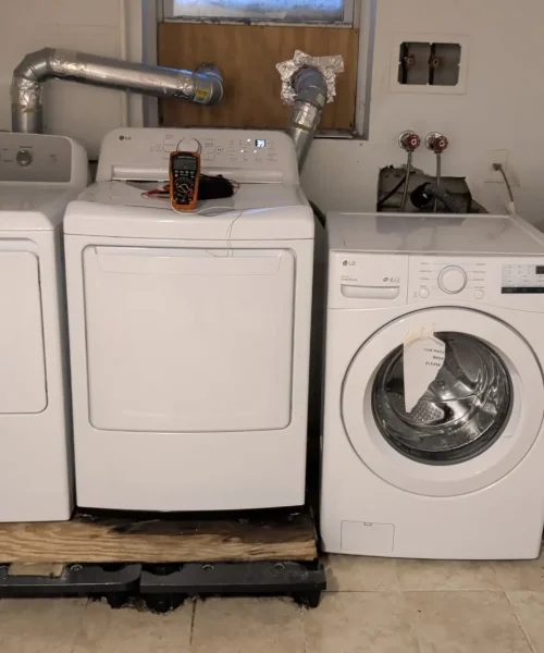 Washer and dryer appliances lined up in a Staten Island basement laundry room.