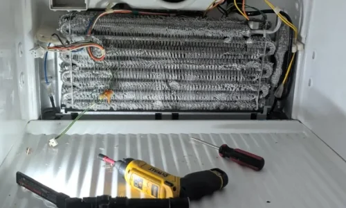 Refrigerator evaporator fan and coil exposed for cooling repair.