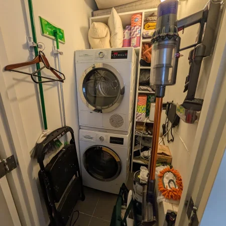 Stacked washer and dryer unit installed in a narrow utility closet.