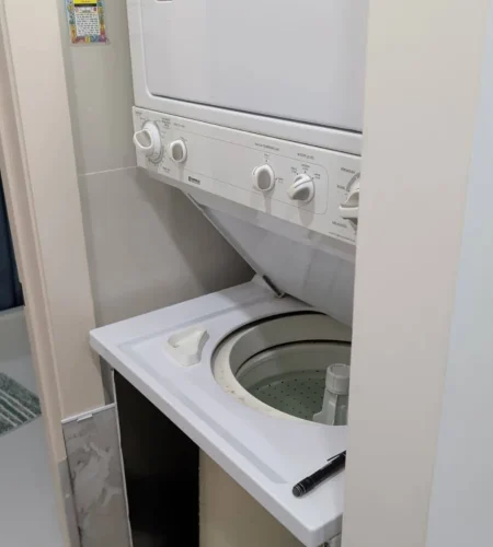 Stacked washer and dryer fitted inside a narrow laundry closet.