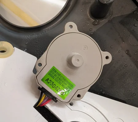 Washer drain pump motor removed from the tub assembly for replacement.
